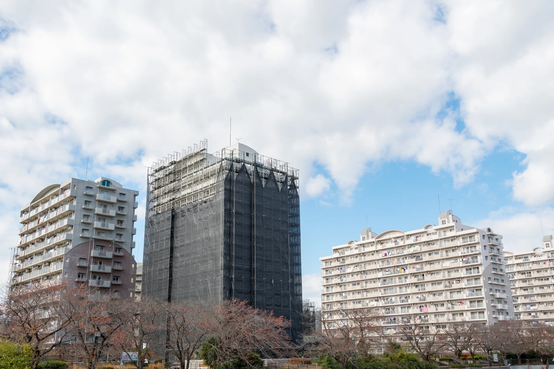 外壁塗装のため足場とシートで覆われたマンション