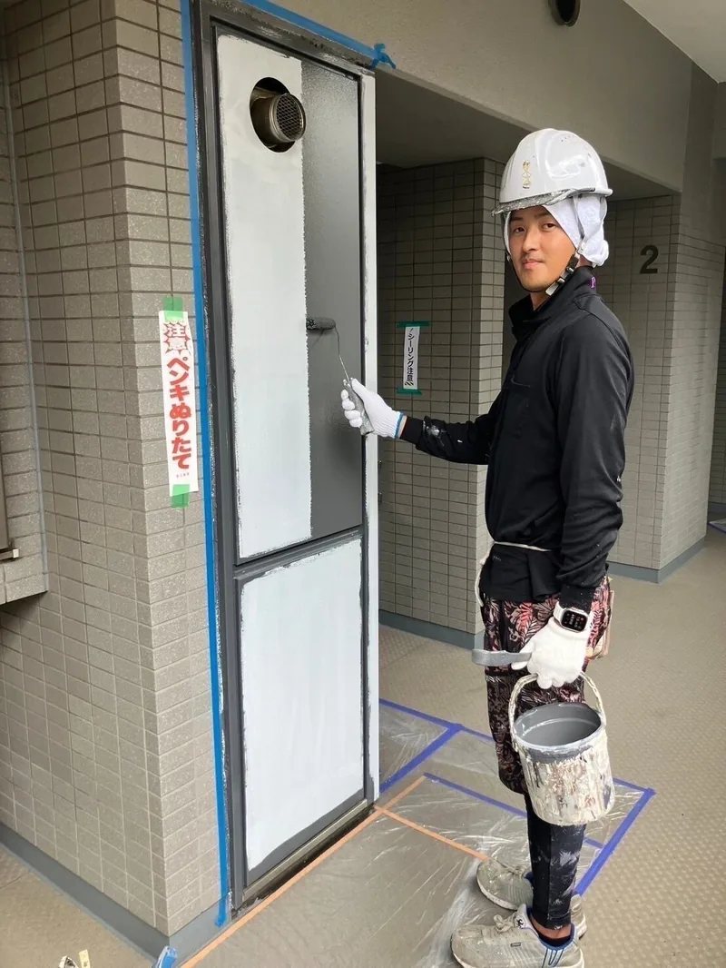 養生した鉄扉を塗装する職人