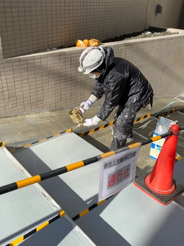 通行止めのコーンを立ててスロープを塗装する職人